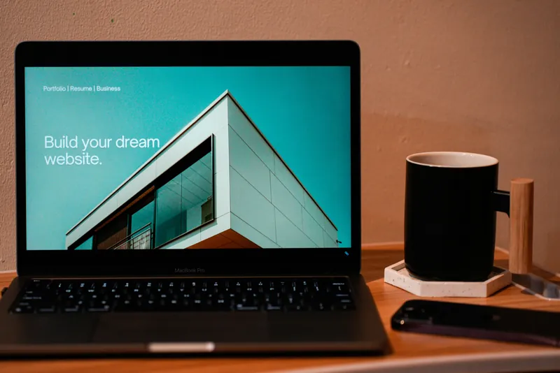 Een laptop op een bureau met een website op het scherm, ernaast een mok